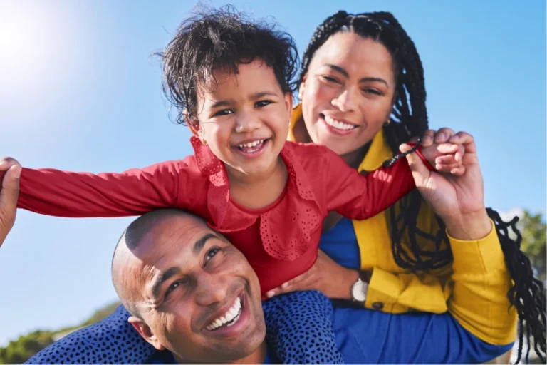 Família de três sorrindo ao ar livre